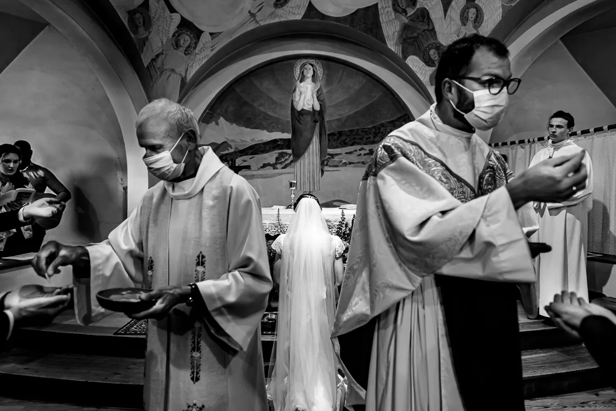 Deux prêtres distribuent la communion pendant que la mariée prie devant la vierge.