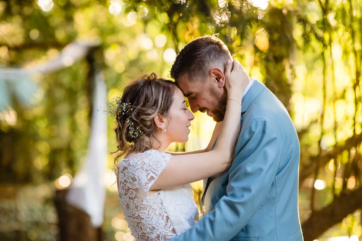 Couple de marié dans un sous bois, devant l'arche de la cérémonie laïque.